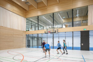 Menschen spielen Basketball in einer modernen Sporthalle.